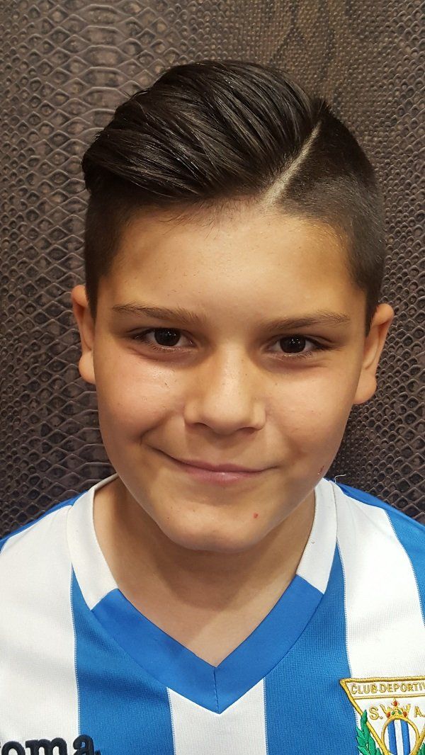 Un niño que lleva una camisa de rayas azules y blancas sonríe a la cámara.