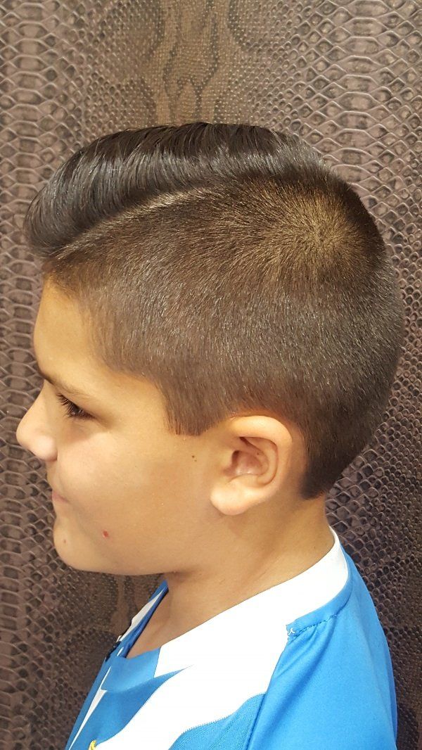 Un niño pequeño con un peinado mohawk lleva una camisa azul.