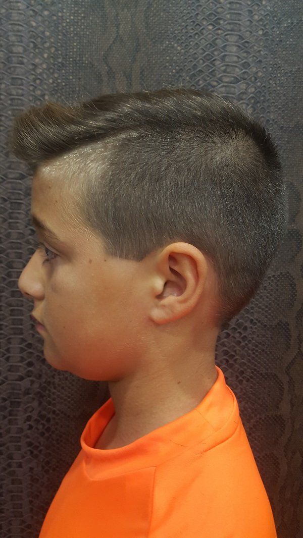 Un niño con un peinado mohawk lleva una camisa naranja.