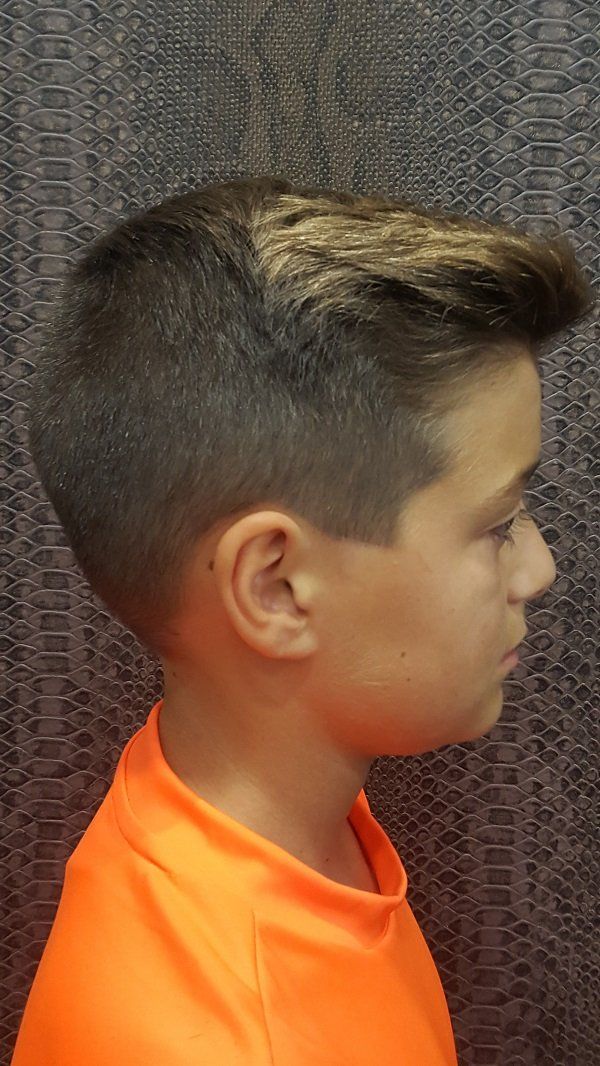 Un niño pequeño con pelo corto lleva una camiseta naranja.