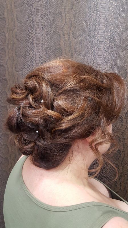 Una mujer lleva una camiseta verde sin mangas y tiene el pelo recogido en un moño.