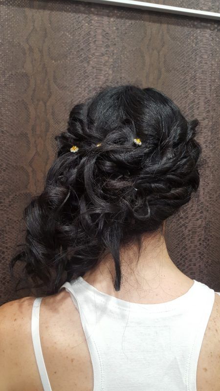 Una mujer lleva una camiseta blanca sin mangas y tiene el pelo recogido en un moño.