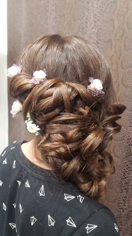 Una mujer lleva un peinado trenzado con flores en el cabello.