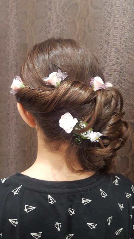 Una mujer lleva un moño con flores en el pelo.