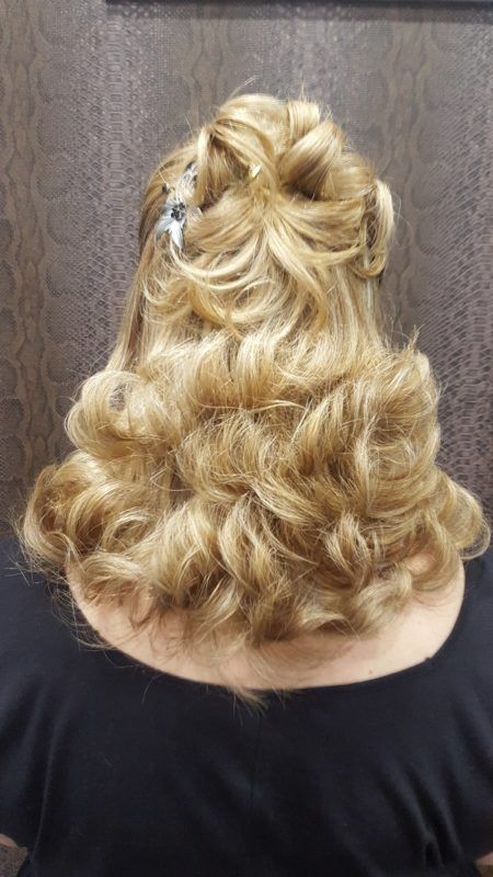 Una mujer con cabello rubio lleva una camisa negra y tiene el cabello recogido en un moño.