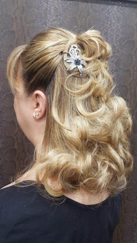 Una mujer lleva el cabello recogido mitad arriba y mitad abajo con una flor en el cabello.