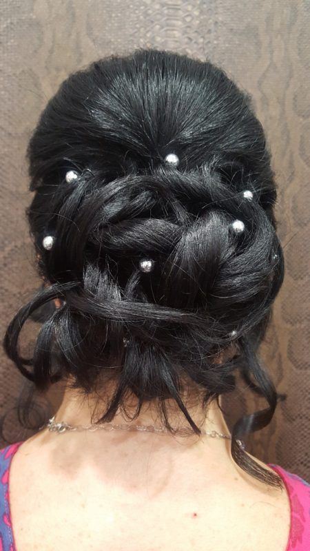 Una mujer lleva el pelo recogido en un moño con perlas.