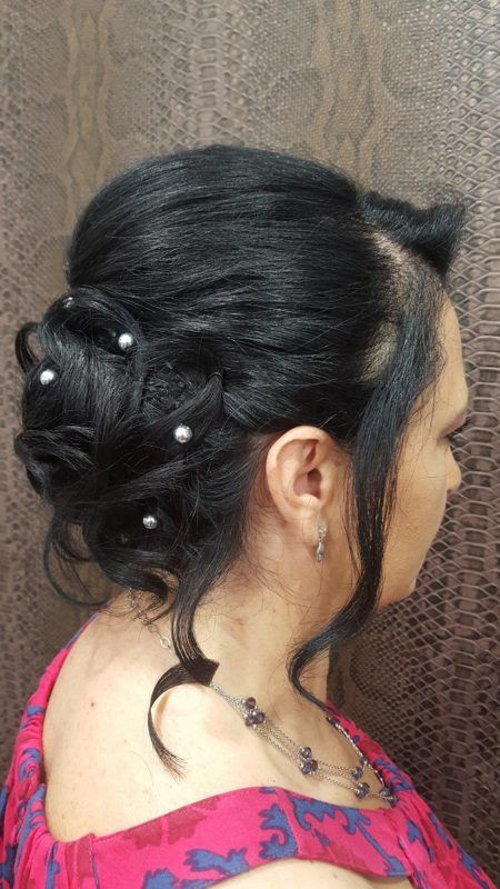 Una mujer lleva un vestido rojo y un moño con perlas en el pelo.