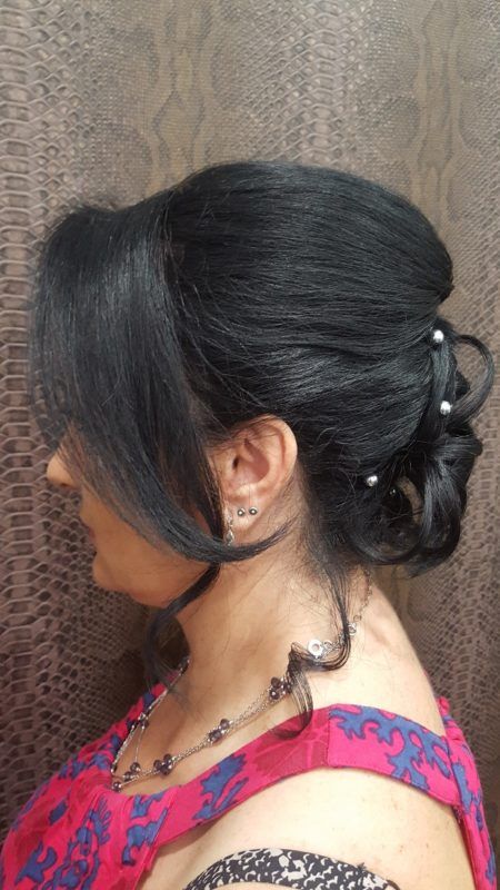 Una mujer lleva un vestido rojo y un moño con perlas en el pelo.