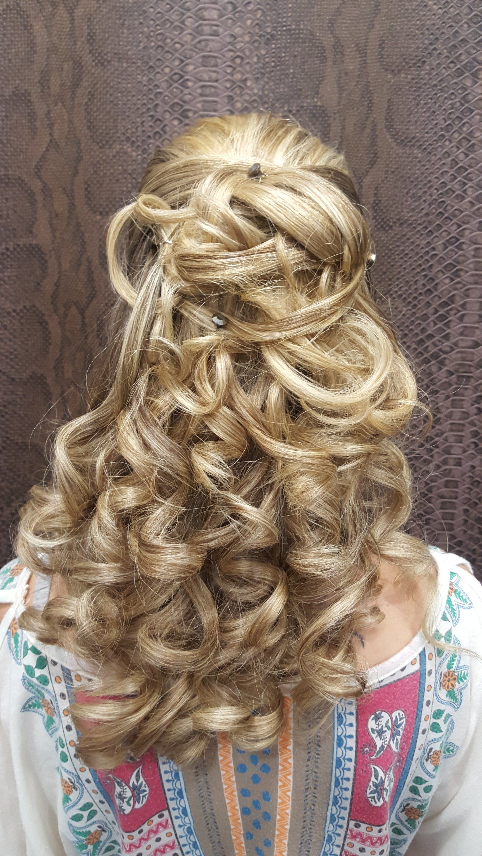 Una mujer con cabello largo rubio y rizado lleva un peinado mitad recogido mitad suelto.