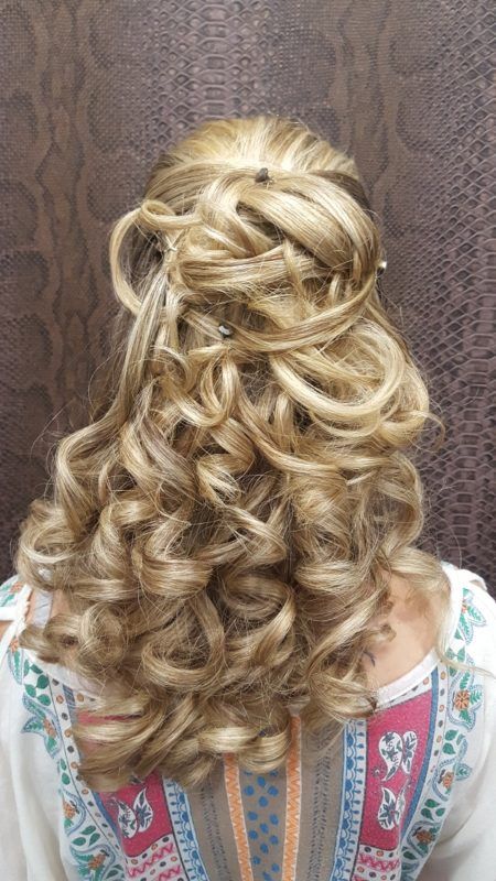 Una mujer con cabello largo rubio y rizado lleva un peinado mitad recogido mitad suelto.