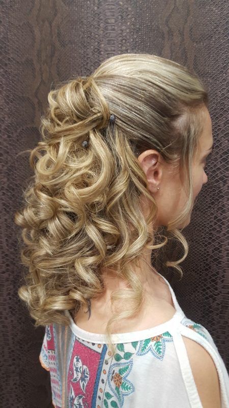 Una mujer lleva un peinado mitad recogido mitad suelto con cabello rizado.