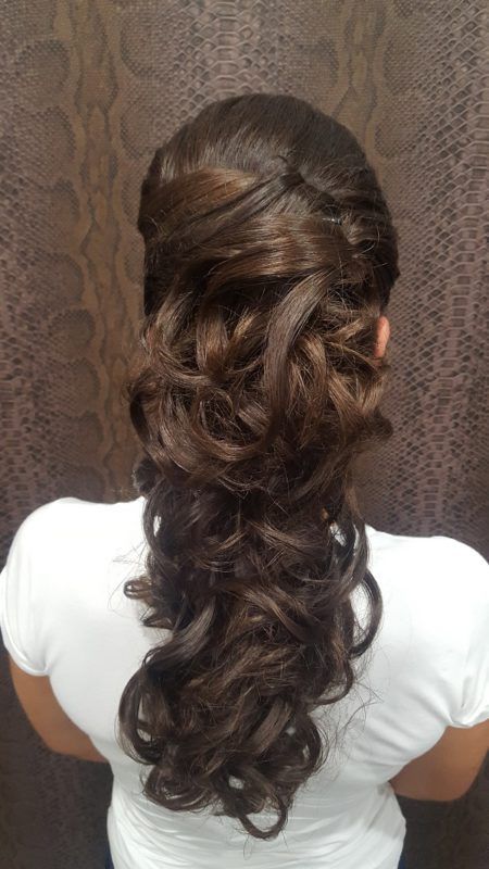 La espalda de una mujer que lleva una camisa blanca y un peinado mitad recogido mitad suelto.