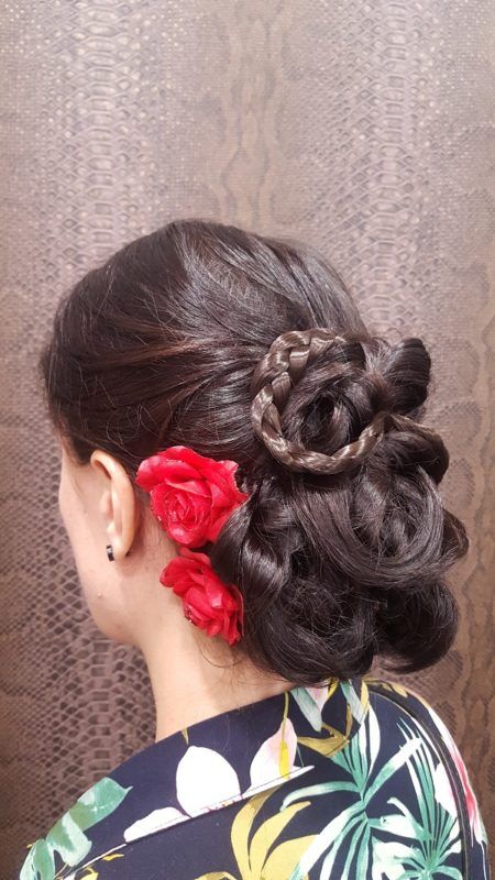 Una mujer lleva un moño con rosas rojas en el pelo.