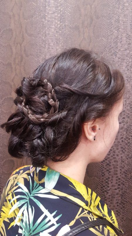 Una mujer lleva una camisa floreada y tiene el pelo recogido en un moño.