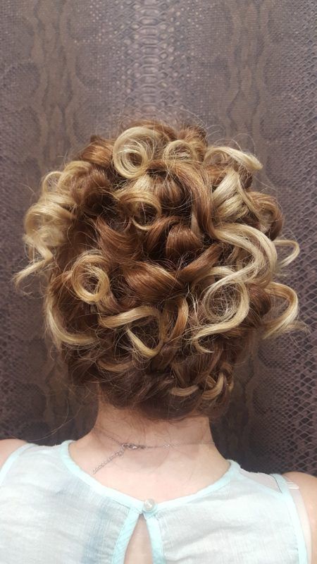 La parte posterior de la cabeza de una mujer con cabello rizado recogido en un moño.