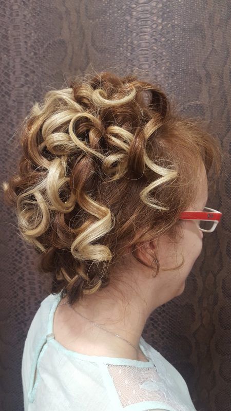 Una mujer con pelo rizado y gafas lleva un moño.