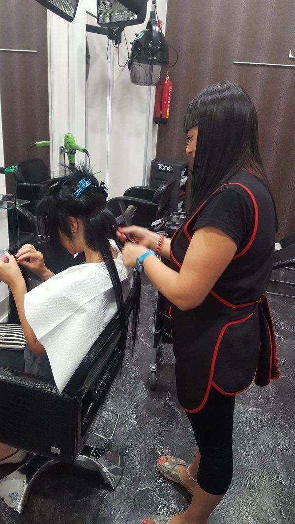 Una mujer está cortando el cabello de otra mujer en un salón.
