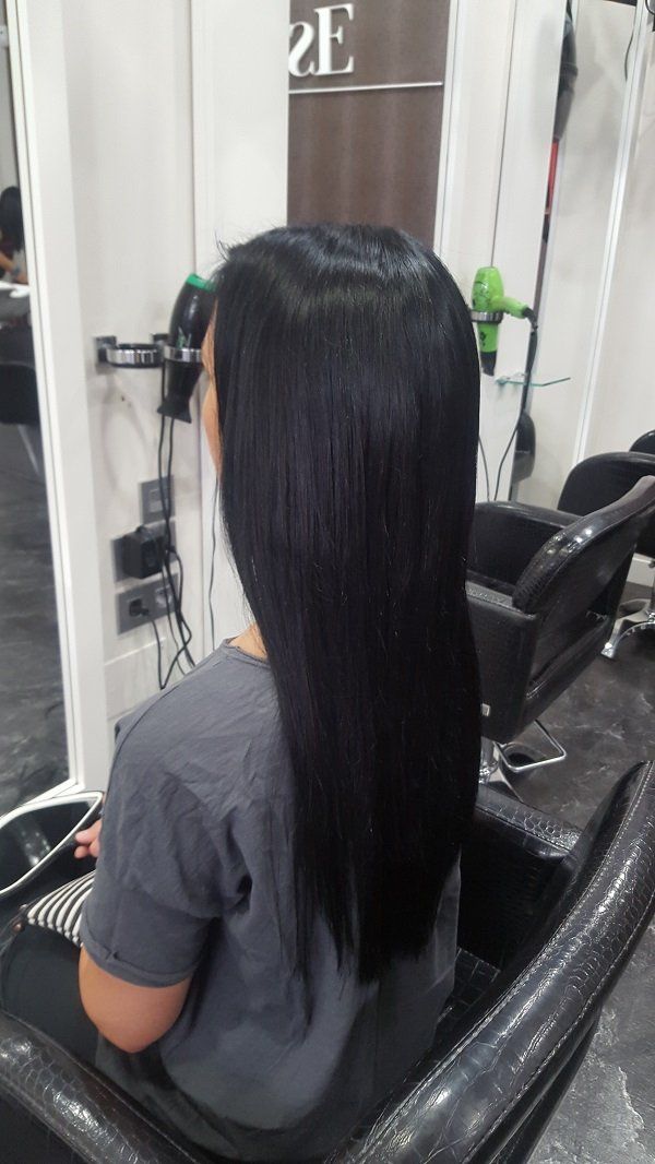 Una mujer con cabello largo y negro está sentada en una silla en un salón.