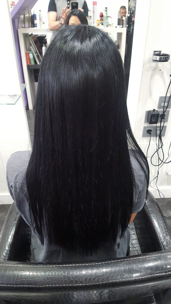 Una mujer con cabello largo y negro está sentada en una silla en un salón.