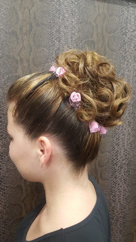 Una mujer lleva el pelo recogido en un moño con flores rosas.