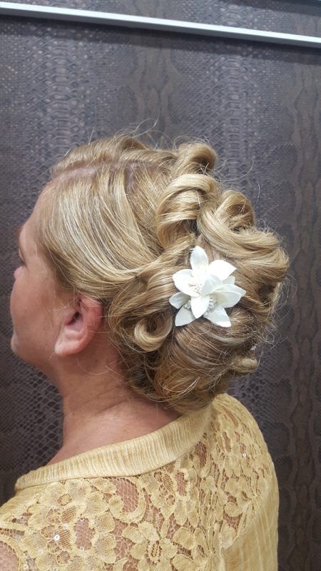Una mujer con cabello rubio recogido en un moño con una flor en el pelo.