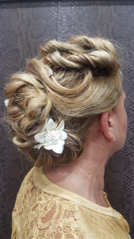 Una mujer con cabello rubio recogido en un moño con una flor en el pelo.