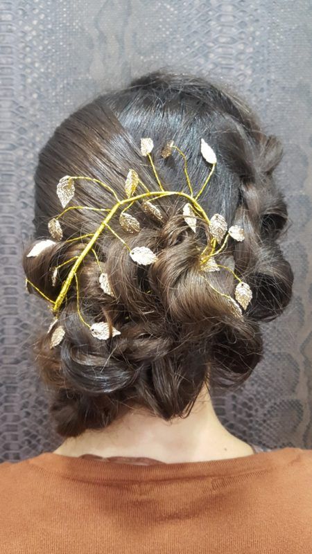 Una mujer lleva un moño con hojas en el pelo.