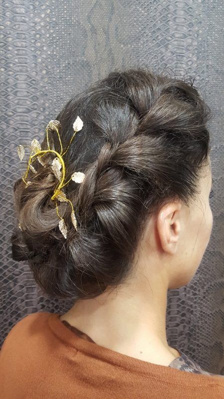 Una mujer lleva un moño trenzado con flores en el pelo.