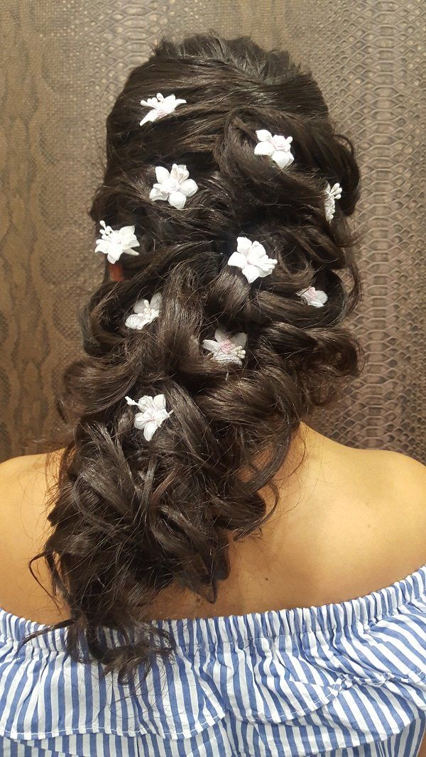 Una mujer lleva un peinado trenzado con flores blancas en el cabello.