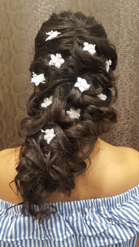 Una mujer lleva un peinado trenzado con flores blancas en el cabello.