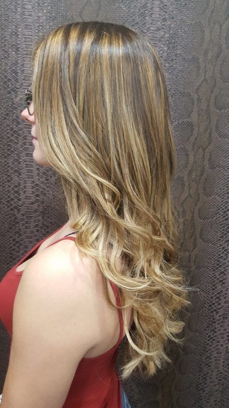 Una mujer con cabello largo y rubio lleva una camiseta roja sin mangas.