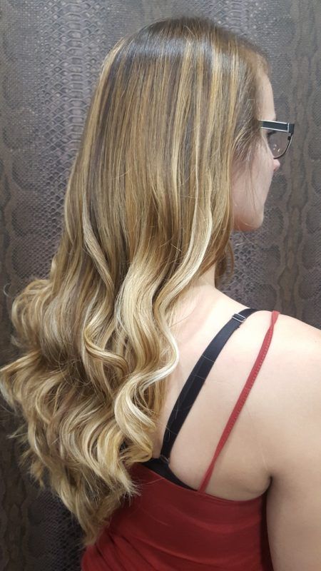 Una mujer con cabello largo y rubio y gafas lleva una camiseta roja sin mangas.