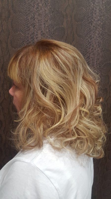 Una mujer con cabello rubio y una camisa blanca está parada frente a una pared.