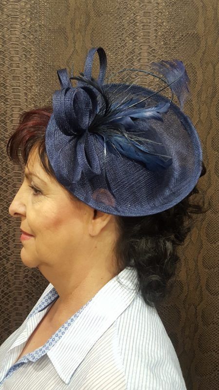 Una mujer que lleva un sombrero azul con plumas.