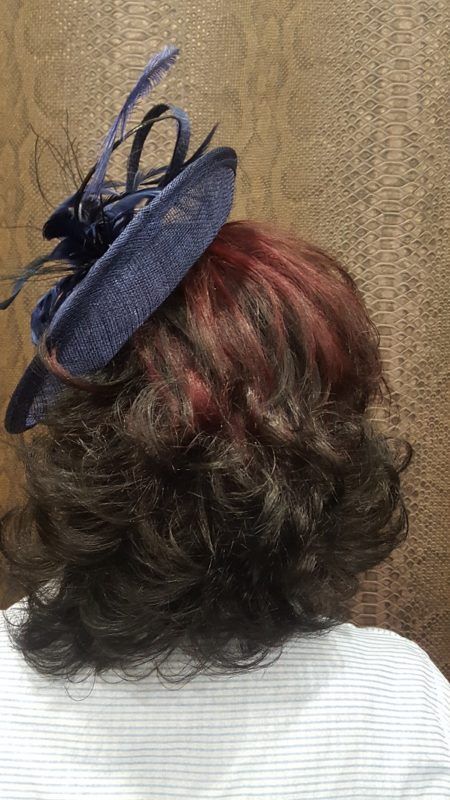 Una mujer lleva un sombrero azul con cabello rojo.