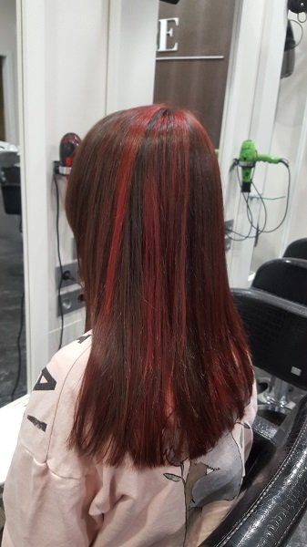 Una mujer con cabello largo y rojo está sentada en una silla en un salón.