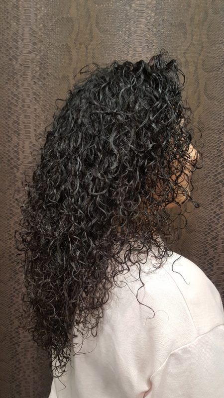 Una mujer con cabello rizado lleva una camisa blanca.