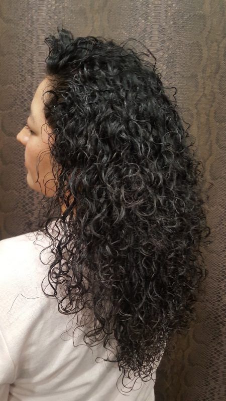 Una mujer con cabello rizado lleva una camisa blanca.