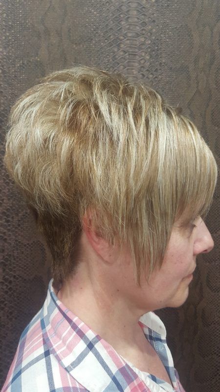 Una mujer con cabello rubio corto lleva una camisa a cuadros.