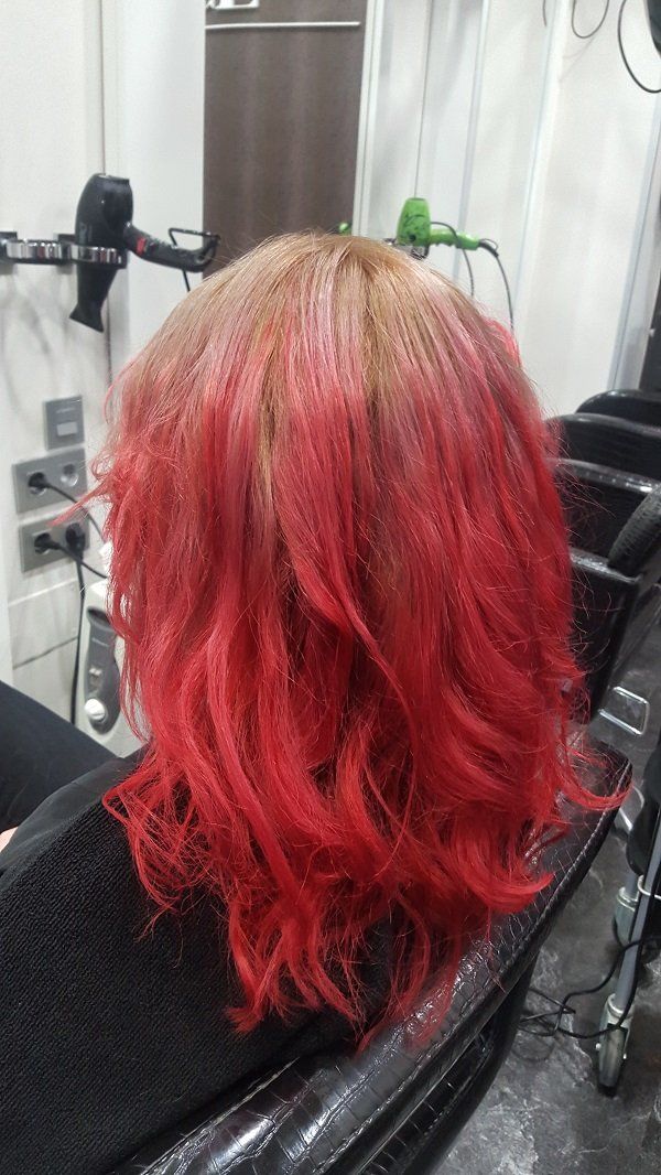 Una mujer con cabello rojo está sentada en una silla en un salón.