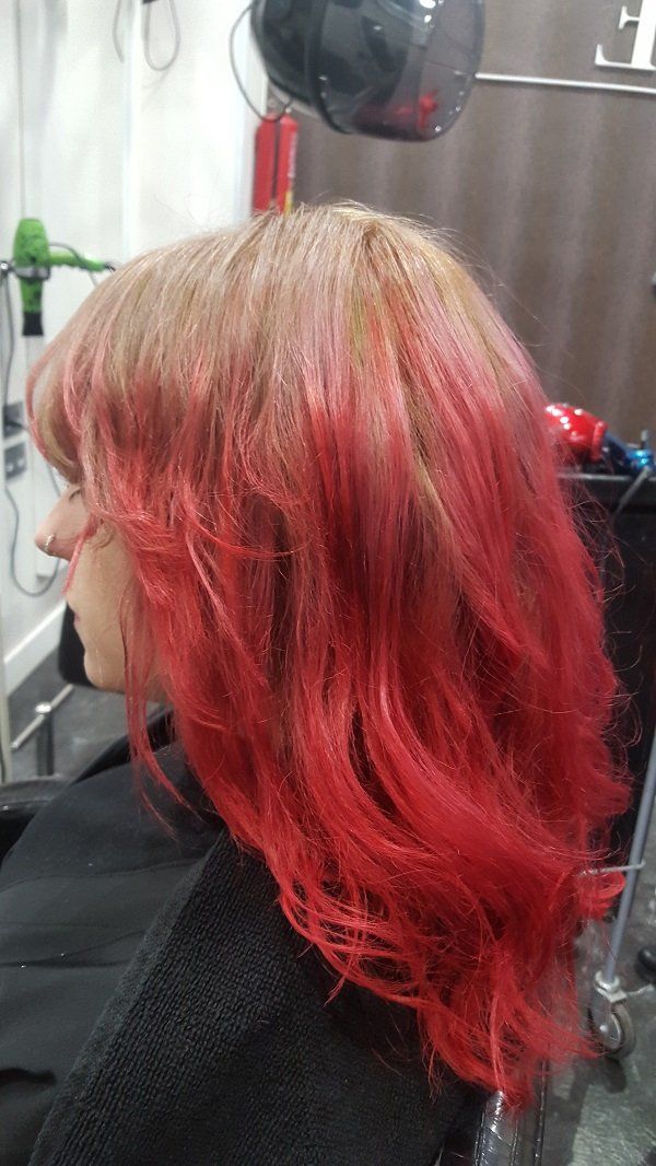 Una mujer con cabello rojo está sentada en una silla en una peluquería.