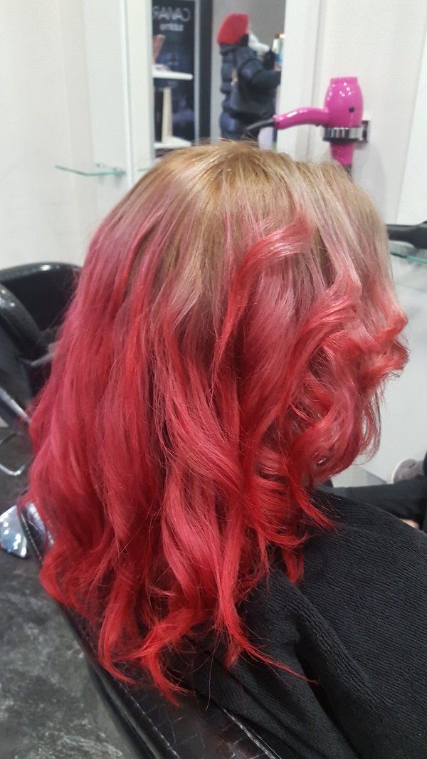 Una mujer pelirroja se está tiñendo el pelo en un salón.