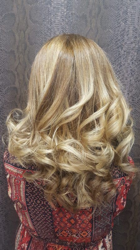 Una mujer con cabello largo rubio y rizado lleva un vestido rojo.