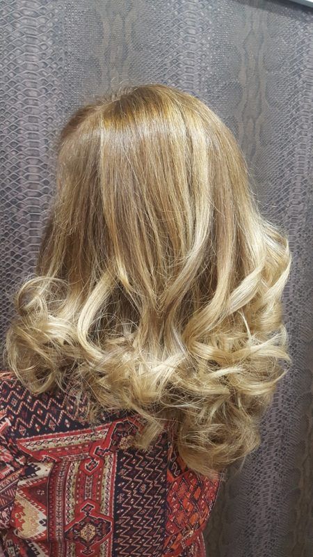 Una mujer con cabello largo y rubio está parada frente a una pared.