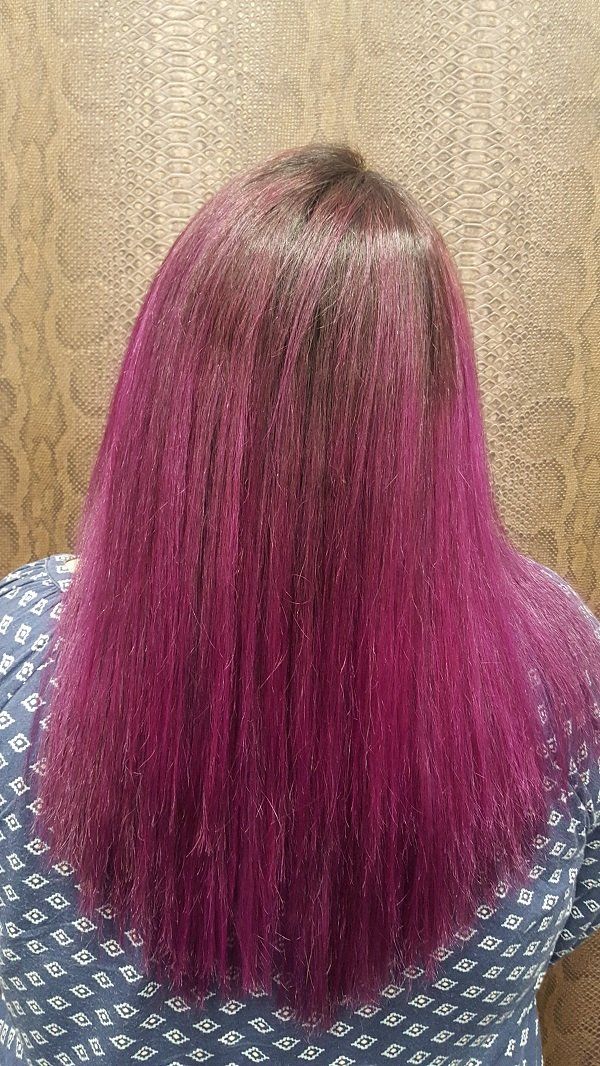 Una mujer con cabello morado lleva una camisa azul.