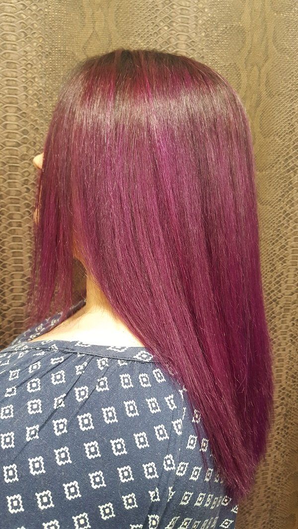 Una mujer con cabello morado lleva una camisa azul.
