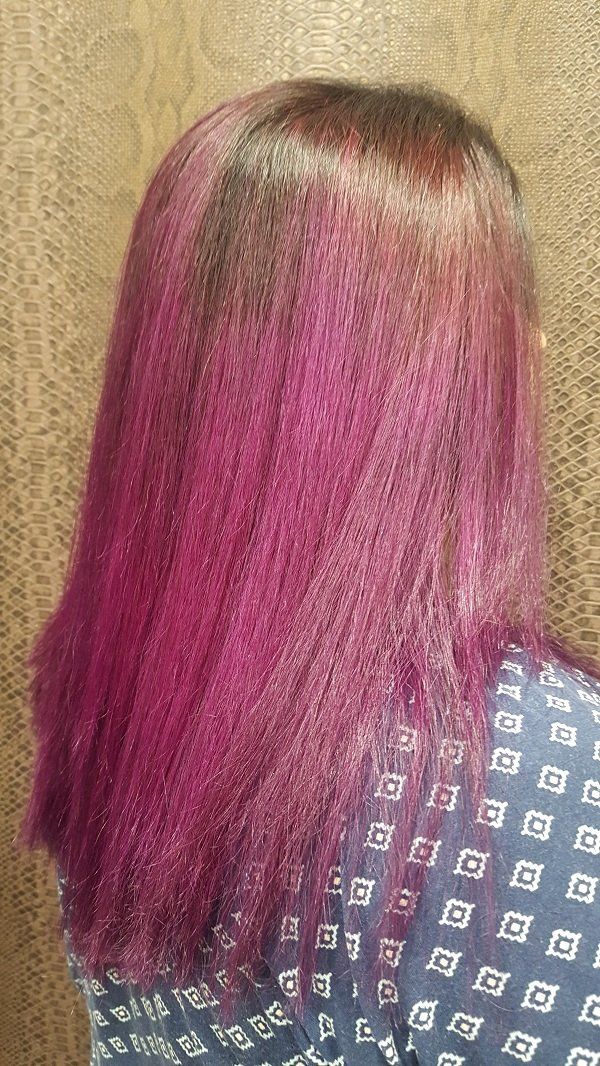 Una mujer con cabello morado lleva una camisa azul.