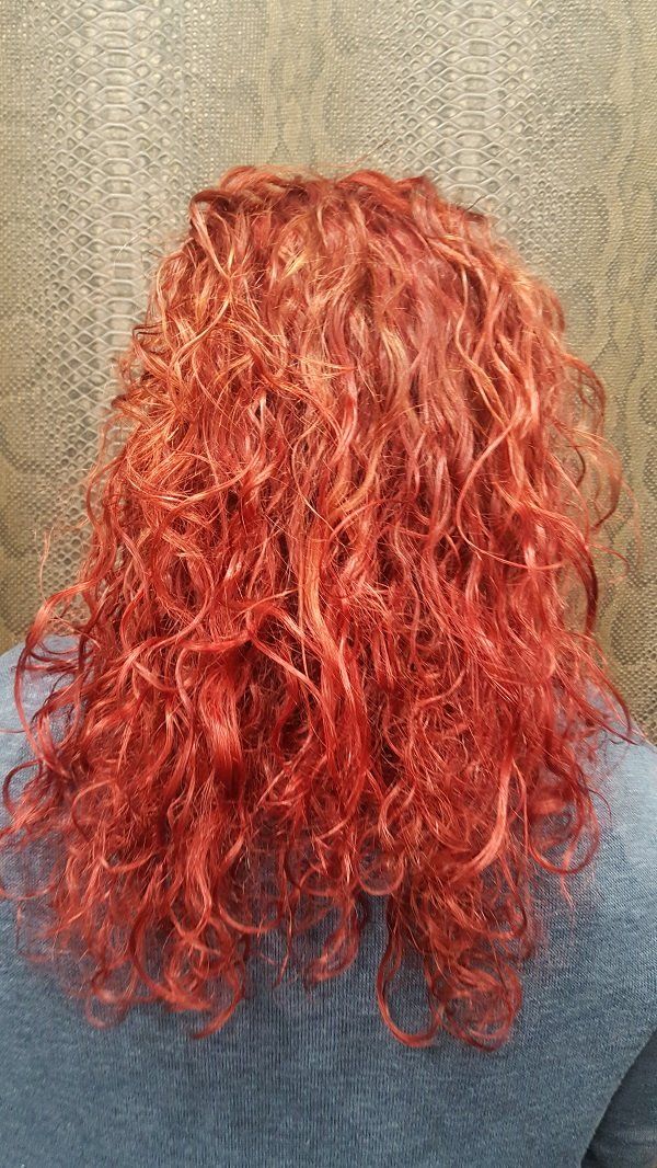 Una mujer con cabello rojo y rizado lleva un suéter azul.