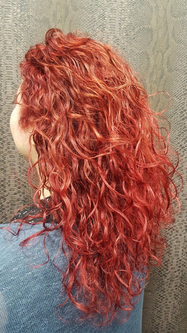 Una mujer con cabello rojo y rizado lleva un suéter azul.